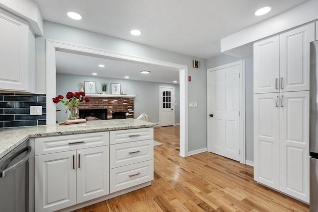 kitchen with light wood-type flooring, backsplash, a peninsula, white cabinets, and dishwasher