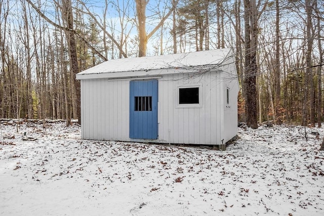 snow covered structure with an outbuilding