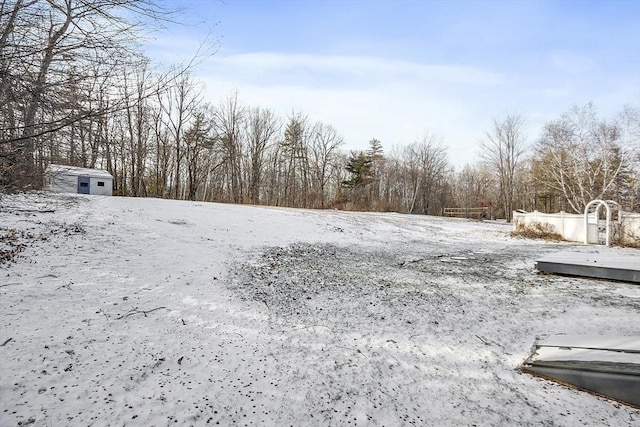 snowy yard featuring an outbuilding and a storage unit