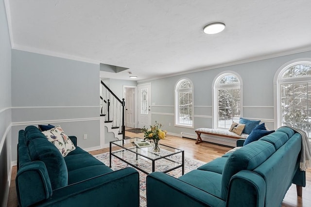 living area featuring stairway, plenty of natural light, wood finished floors, and a baseboard heating unit