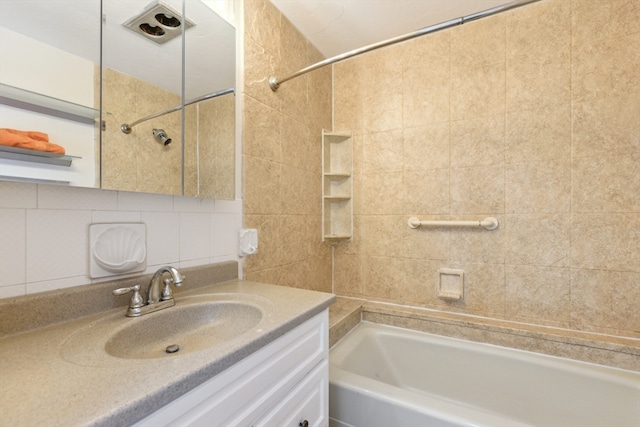 bathroom with vanity, backsplash, tile walls, and tiled shower / bath combo