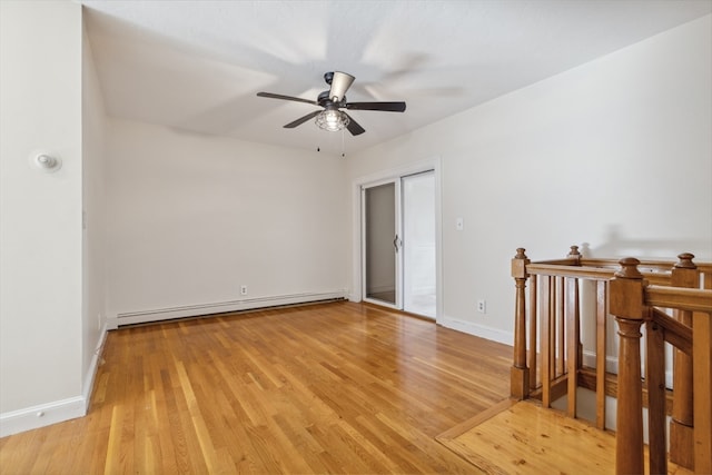 unfurnished room with a baseboard heating unit, light wood-type flooring, and ceiling fan