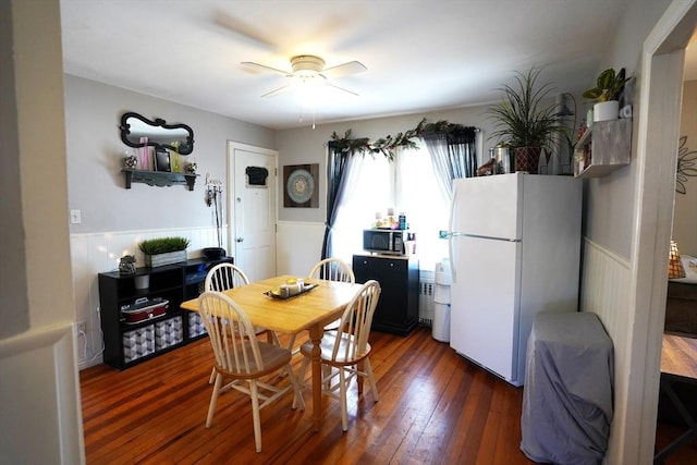 dining area with ceiling fan, wainscoting, and hardwood / wood-style flooring