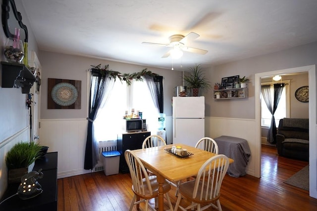 dining room featuring a wainscoted wall, ceiling fan, hardwood / wood-style floors, and a healthy amount of sunlight