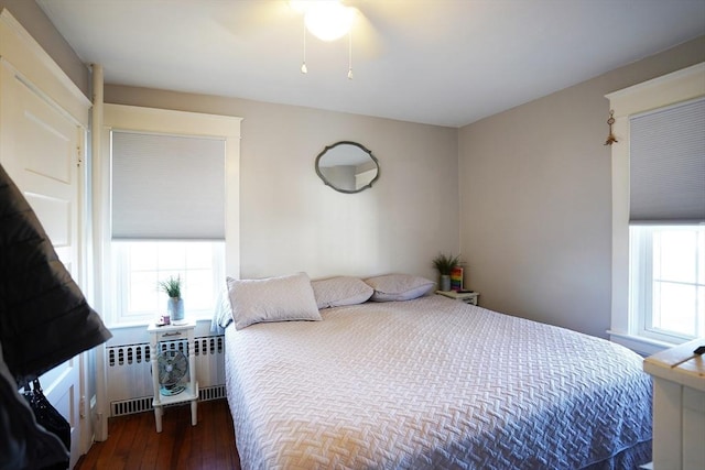 bedroom with radiator heating unit, wood finished floors, and a ceiling fan