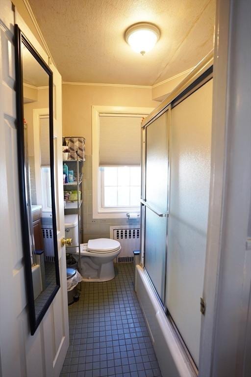 full bath with radiator, toilet, tile patterned flooring, combined bath / shower with glass door, and a textured ceiling