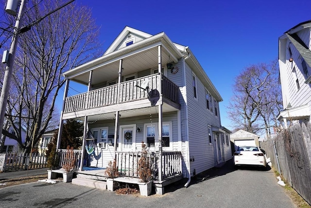 view of front of property with a balcony, covered porch, driveway, and fence