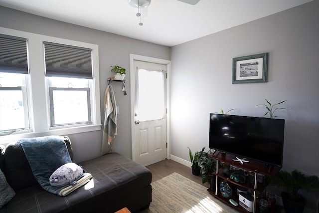 living area with wood finished floors, a ceiling fan, and baseboards