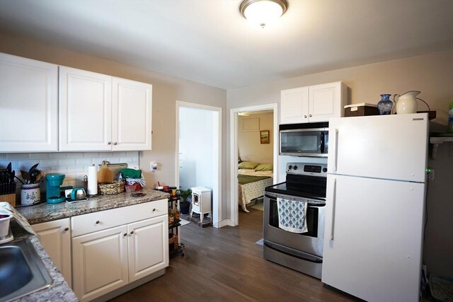 kitchen featuring stainless steel appliances, dark wood finished floors, backsplash, and white cabinetry