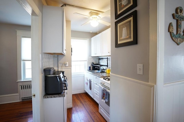 kitchen with dark wood-style floors, radiator, white cabinets, and white range with gas stovetop