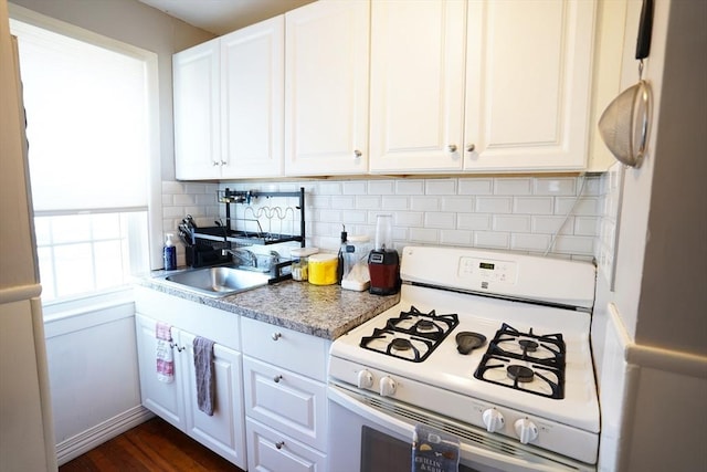 kitchen featuring white appliances, decorative backsplash, light countertops, white cabinetry, and a sink