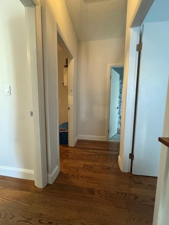 hall featuring a textured ceiling and dark hardwood / wood-style flooring