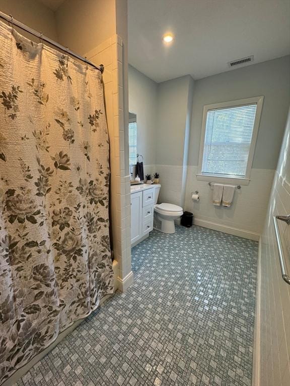 bathroom with vanity, toilet, a shower with shower curtain, and tile walls