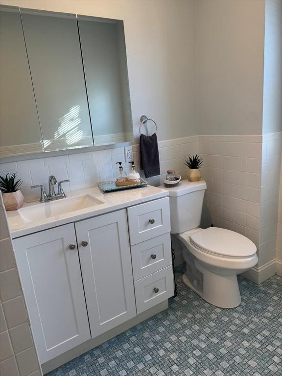 bathroom with vanity, tile walls, and toilet