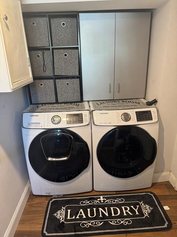 clothes washing area with separate washer and dryer, dark hardwood / wood-style flooring, and cabinets