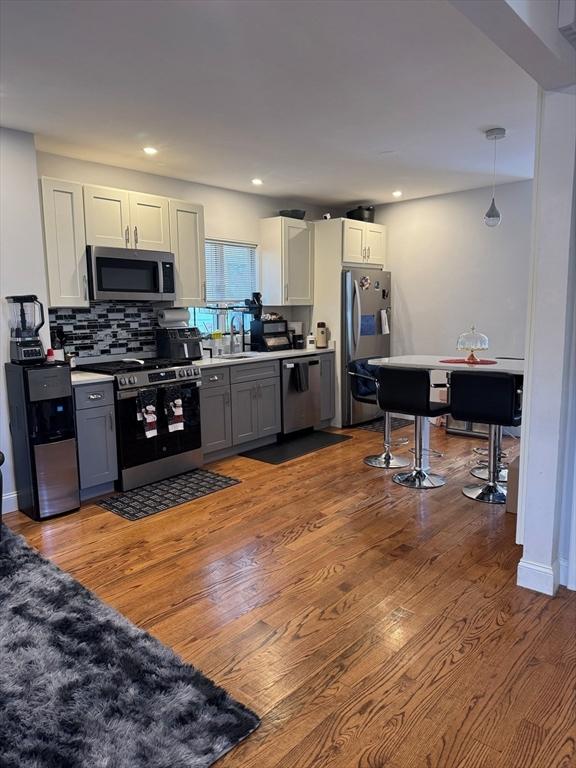 kitchen with gray cabinets, appliances with stainless steel finishes, decorative light fixtures, sink, and white cabinets