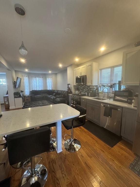 kitchen featuring pendant lighting, white cabinetry, sink, hardwood / wood-style flooring, and stainless steel appliances