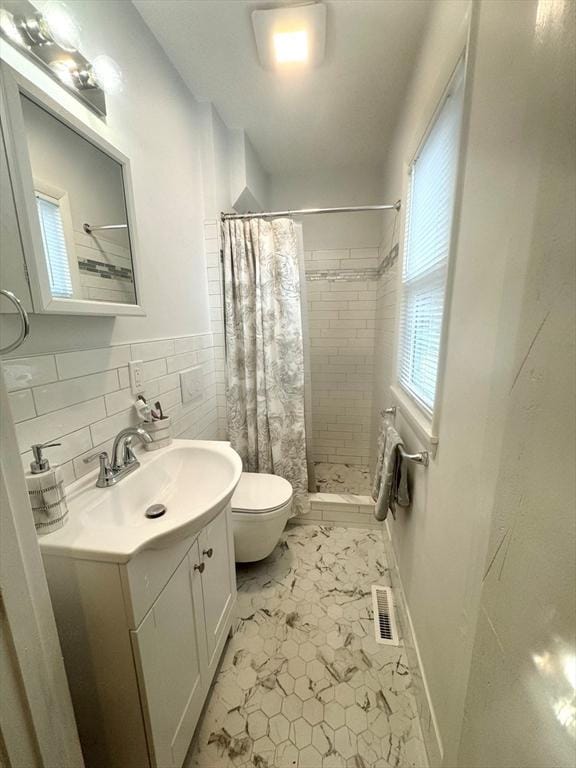 bathroom with toilet, a shower with curtain, tasteful backsplash, tile walls, and vanity