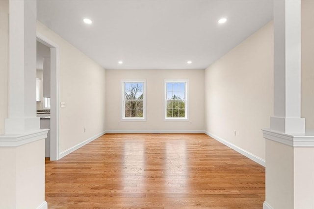 spare room featuring baseboards, light wood finished floors, decorative columns, and recessed lighting