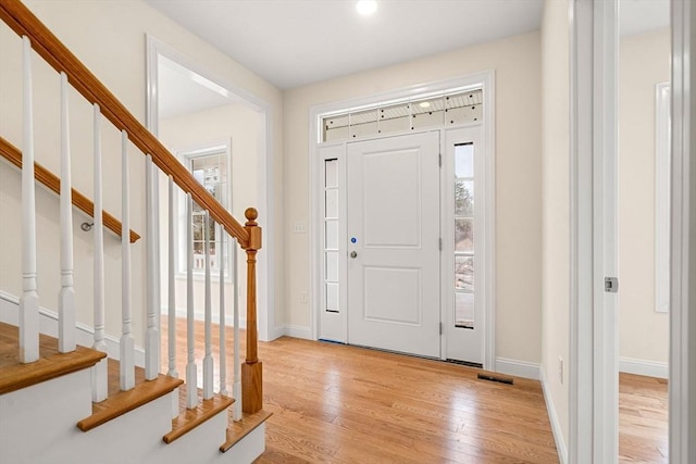 entryway featuring baseboards, stairway, and light wood-style floors