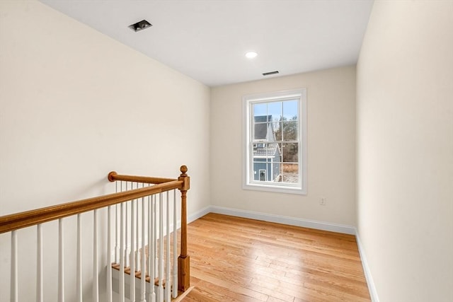 empty room with hardwood / wood-style floors, visible vents, and baseboards