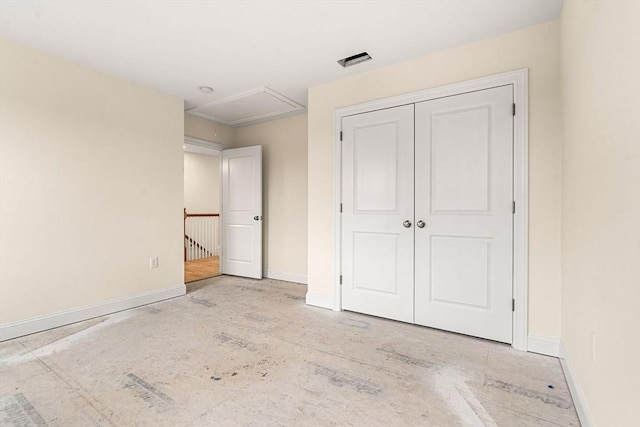 unfurnished bedroom featuring visible vents, attic access, baseboards, and a closet