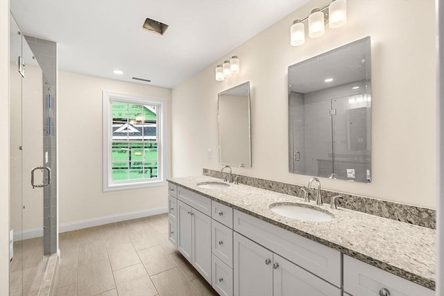 full bathroom featuring a sink, a shower stall, baseboards, and double vanity