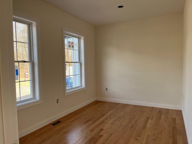 unfurnished room with visible vents, light wood-style flooring, and baseboards