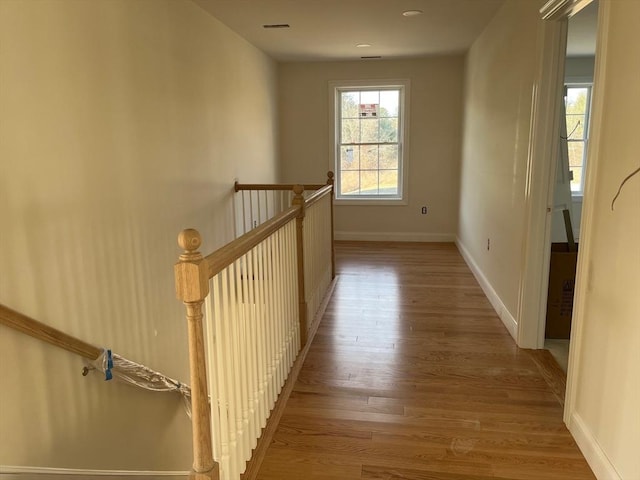 hallway featuring wood finished floors, an upstairs landing, and baseboards