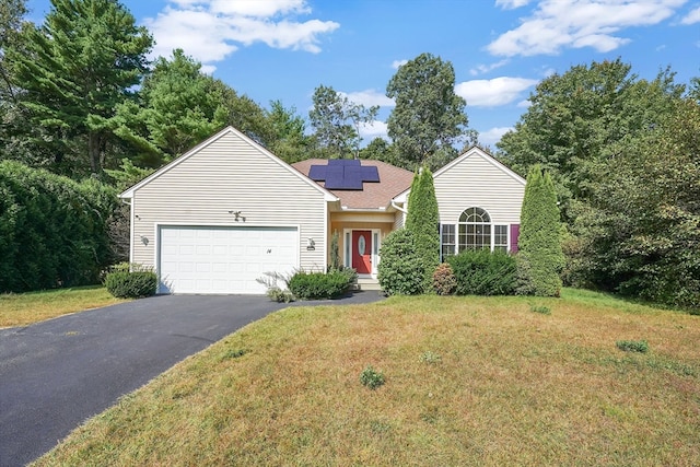 view of front of house with a garage, solar panels, and a front lawn