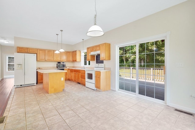 kitchen featuring decorative light fixtures, light tile patterned floors, white appliances, and a center island