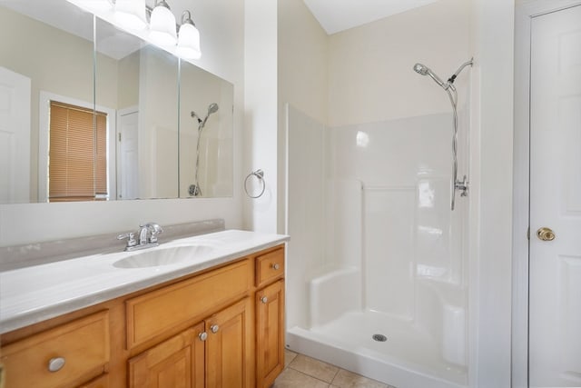 bathroom with a shower, tile patterned flooring, and vanity