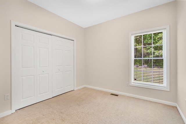 unfurnished bedroom featuring a closet, multiple windows, and light colored carpet