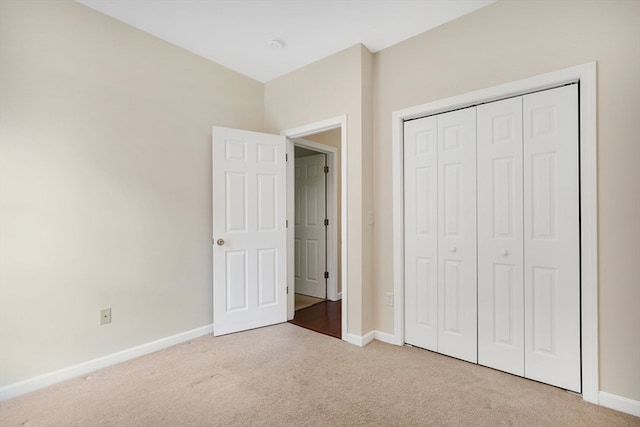 unfurnished bedroom featuring a closet and light colored carpet