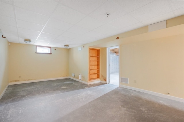 unfurnished room featuring a drop ceiling and concrete flooring