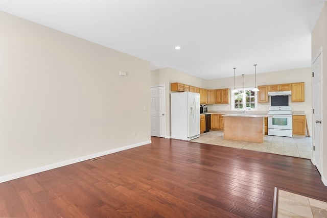 kitchen featuring sink, a kitchen island, light hardwood / wood-style flooring, white appliances, and decorative light fixtures