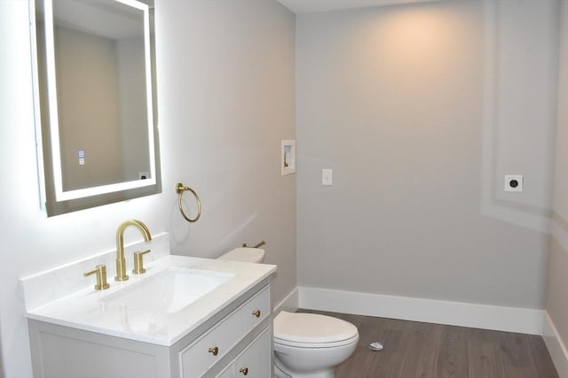 bathroom with toilet, baseboards, wood finished floors, and vanity