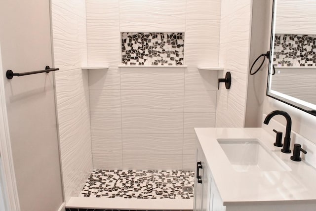 full bathroom featuring a tile shower, vanity, and tile walls