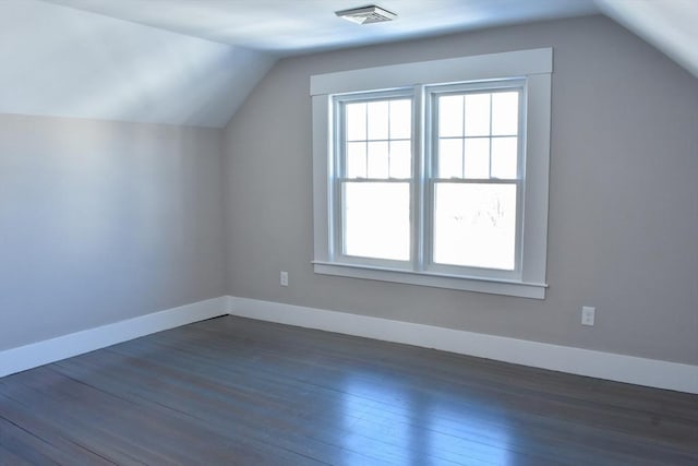 bonus room featuring dark wood-style flooring, visible vents, vaulted ceiling, and baseboards