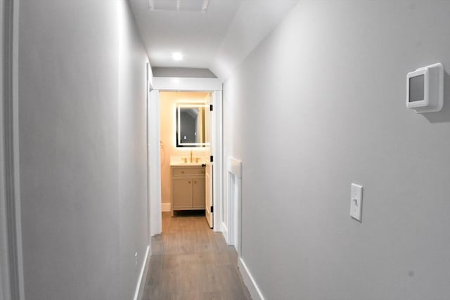 corridor with visible vents, baseboards, and wood finished floors