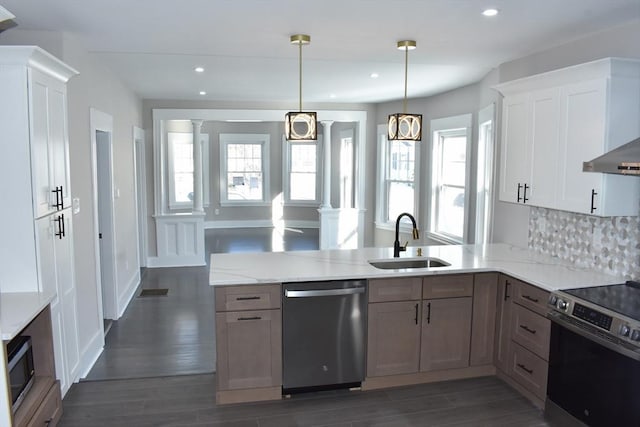 kitchen with dark wood-style floors, a peninsula, stainless steel appliances, ornate columns, and a sink