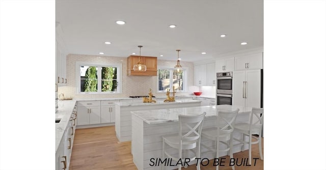 10 Webber Ave Unit 4D, Bedford, MA 01730 - kitchen featuring a center island, stainless steel double oven, a breakfast bar, white cabinets, and recessed lighting