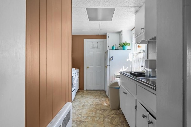 kitchen featuring white cabinets, a paneled ceiling, white fridge, and stove