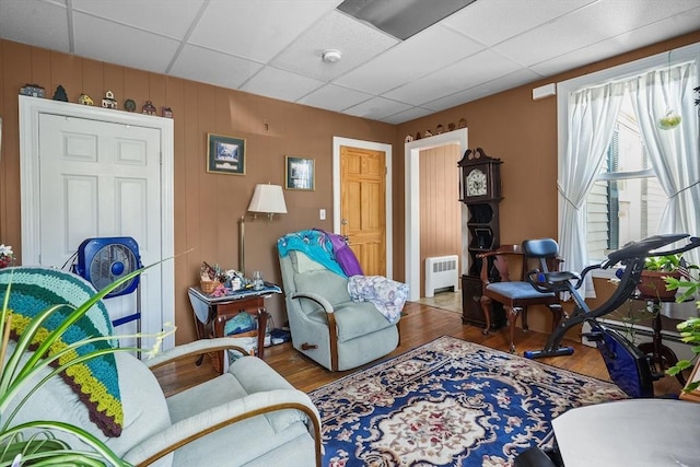 interior space featuring radiator, a paneled ceiling, wooden walls, and dark hardwood / wood-style floors