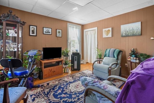 living room featuring baseboard heating, wooden walls, and wood-type flooring