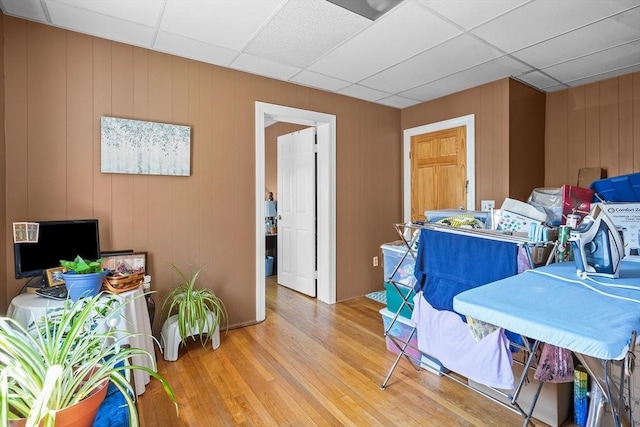 interior space featuring a paneled ceiling, wood walls, and hardwood / wood-style flooring