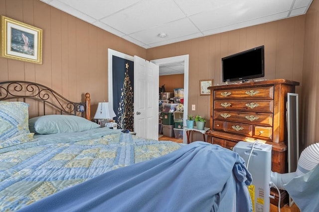 bedroom featuring a drop ceiling and wood walls