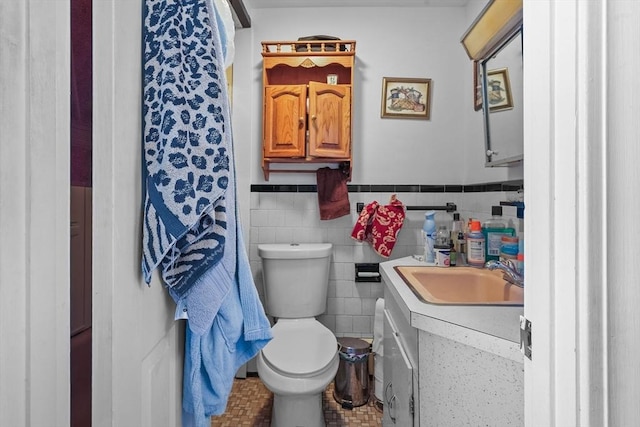 bathroom with vanity, toilet, and tile walls