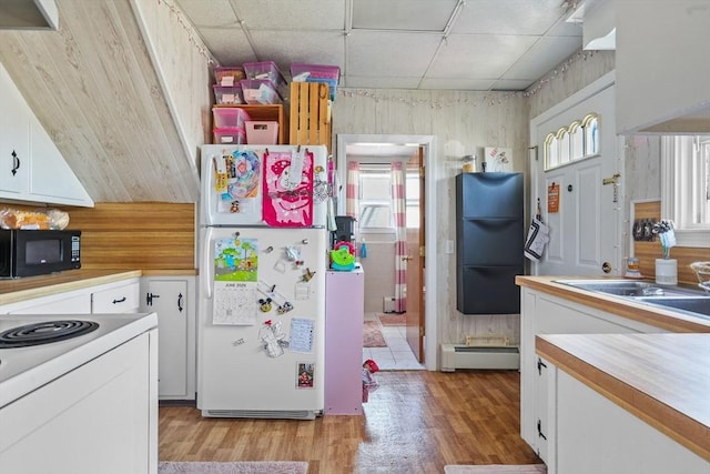 kitchen featuring a paneled ceiling, wood walls, black appliances, white cabinets, and a baseboard radiator