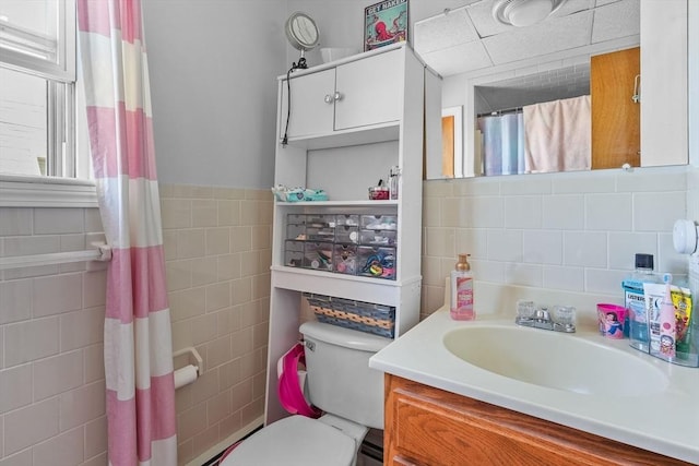 bathroom with vanity, tile walls, and toilet